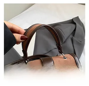 Detail showing the comfortable handle of the brown patchwork handbag with white stitching