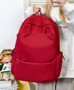 Detail of red high-capacity backpack with gothic embroidery and durable nylon fabric