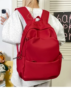 Detail view of large red backpack featuring side pockets and durable textured fabric