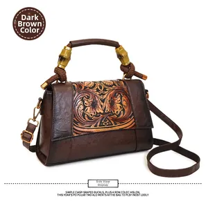 Detail of dark brown vintage leather handbag with embossed floral patterns and bamboo handle
