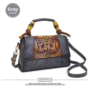 Detailed close-up of retro floral embossed leather bag with bamboo handle design