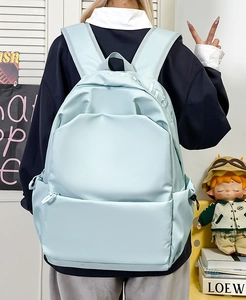 Detailed back view of a mint blue waterproof nylon backpack with white embroidery