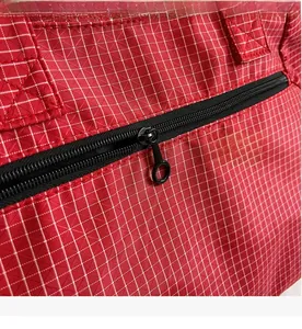 Close-up of smooth black metal zipper and detailed red checkered fabric on tote bag