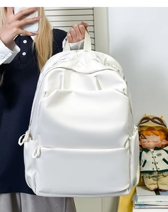 Detail of white minimalist backpack featuring gothic letter embroidery and large front pocket