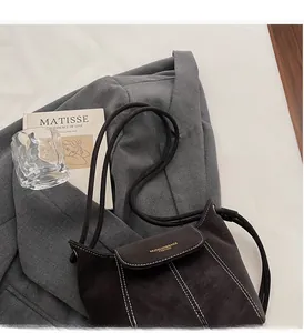 Detail of dark brown suede bucket bag with white contrast stitching and gold logo lettering