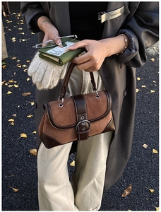 Detail of vintage patchwork handbag featuring brown suede and leather with metal buckle
