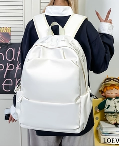 Detail view of white leather backpack texture and embossed lettering on high capacity bag