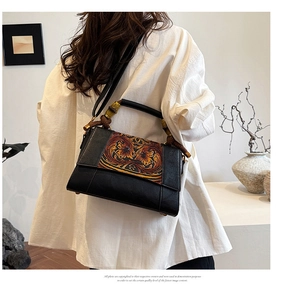 Detail of vintage floral relief on a black shoulder bag with stylish bamboo accents