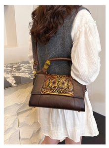 Detail of vintage embossed floral pattern on brown leather bag with bamboo handle