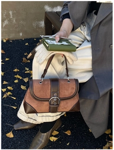 Detail of vintage brown suede tote with metal ring buckle and white stitching