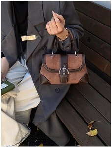 Detail of vintage brown tote with contrast stitching and oversized metal buckle closure