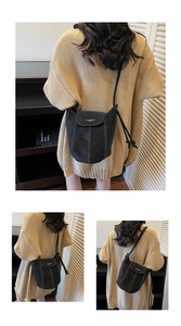 Detail of black suede bucket bag featuring high-contrast white stitching and crossbody strap