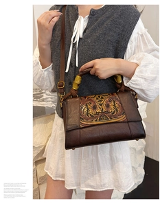 Macro detail of a vintage brown handbag featuring bamboo handles and floral carving