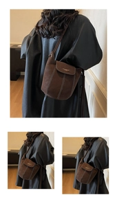 Detail of brown suede bucket bag featuring contrast white stitching and minimalist shoulder strap