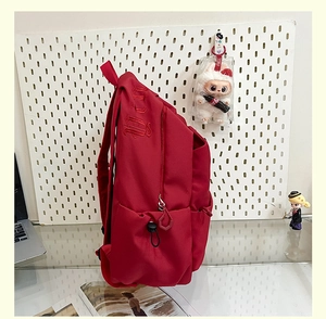 Detail of red travel backpack featuring gothic embroidery and side adjustment buckle