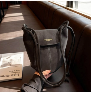 Detail of black suede bucket bag with white contrast stitching and gold foil logo