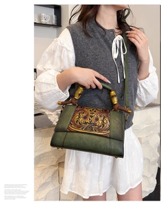 Detail of vintage green leather bag showing carved floral relief and bamboo handle