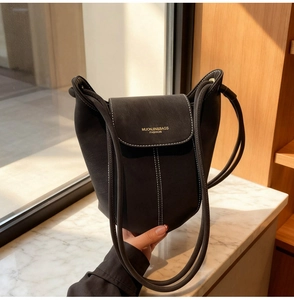 Detail of dark grey bucket bag showing white contrast stitching and soft matte texture