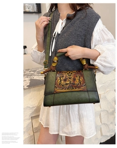 Detail of vintage green leather handbag featuring ornate floral carving and bamboo handle