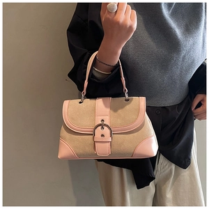 Detail of pink leather and khaki suede patchwork handbag with silver clasp on a model