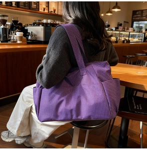 Detail of purple plaid canvas tote bag showing wide shoulder strap and side pocket