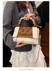 Close-up of vintage shoulder bag featuring bamboo handle and embossed floral detailing