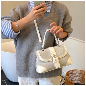 Close-up of grey and off-white paneled crossbody bag with metallic buckle detail