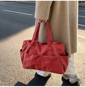 Detail of red plaid tote bag with spacious side pocket shown in street style photography