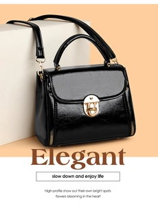 Detail of glossy black patent leather handbag featuring gold hardware and removable strap