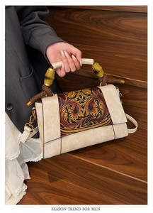 Detail of vintage beige leather bag featuring floral embossing and bamboo handle