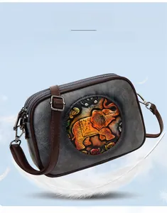 Détail du sac bandoulière rétro avec motif éléphant en relief et double fermeture éclair