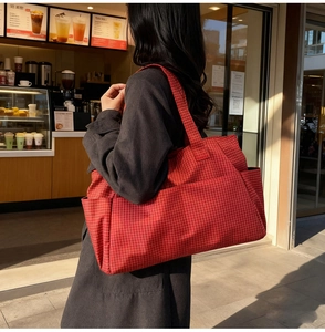 Close-up of red plaid tote bag featuring a practical side pocket and durable canvas strap