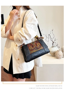 Close-up of vintage black leather bag with embossed floral pattern and bamboo handle details