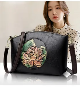 Detail of elegant black leather shell bag with 3D lotus flower embroidery and brown strap