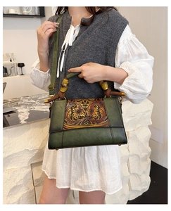 Detailed close-up of retro green leather handbag with floral embossing and bamboo handle