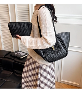 Detail of black woven tote bag and clutch set featuring gold metal buckle clasp