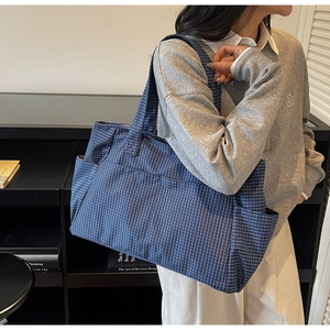 Detail of dark blue checkered tote bag showing side pockets and large capacity design