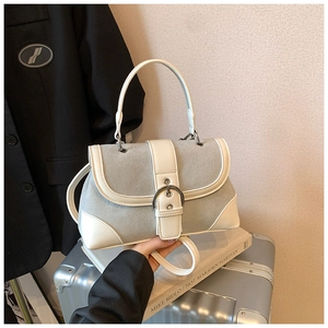 Detail of a retro patchwork handbag featuring grey suede and white leather on a silver suitcase