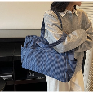 Detail of blue and white checkered tote bag featuring multiple pockets and wide straps
