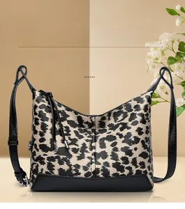 Dettaglio borsa leopardata in tela con base in pelle nera e tracolla regolabile