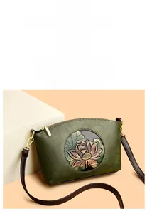 Detail of green shell-shaped crossbody bag featuring an embossed lotus floral pattern