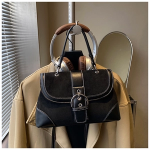 Detailed view of retro black tote bag with white stitching and oversized silver metal buckle