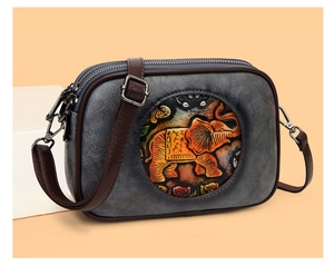 Détail du sac bandoulière rétro en cuir gris avec relief d'éléphant orange artistique