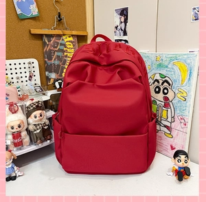 Macro shot of red canvas backpack featuring gothic letter embroidery and zipper pocket