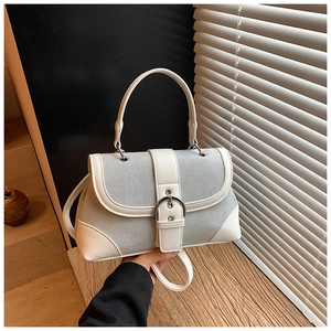 Detail of grey suede and white leather patchwork handbag with silver buckle and handle