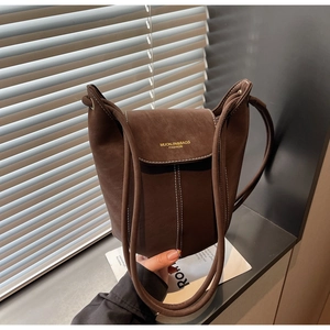 Detail of brown faux suede bucket bag featuring contrast stitching and gold logo
