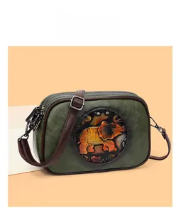 Gros plan d'un sac Boston vintage vert avec embossage d'éléphant et fermeture éclair métallique
