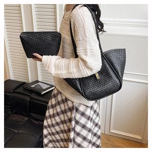 Detail of black woven texture tote bag and matching clutch set on a model