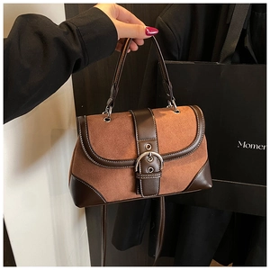 Close-up of vintage brown suede and leather patchwork handbag with metallic buckle