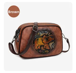 Détail d'un sac en cuir marron avec motif éléphant embossé et double fermeture éclair